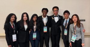 Seven students stand together, smiling at the camera.